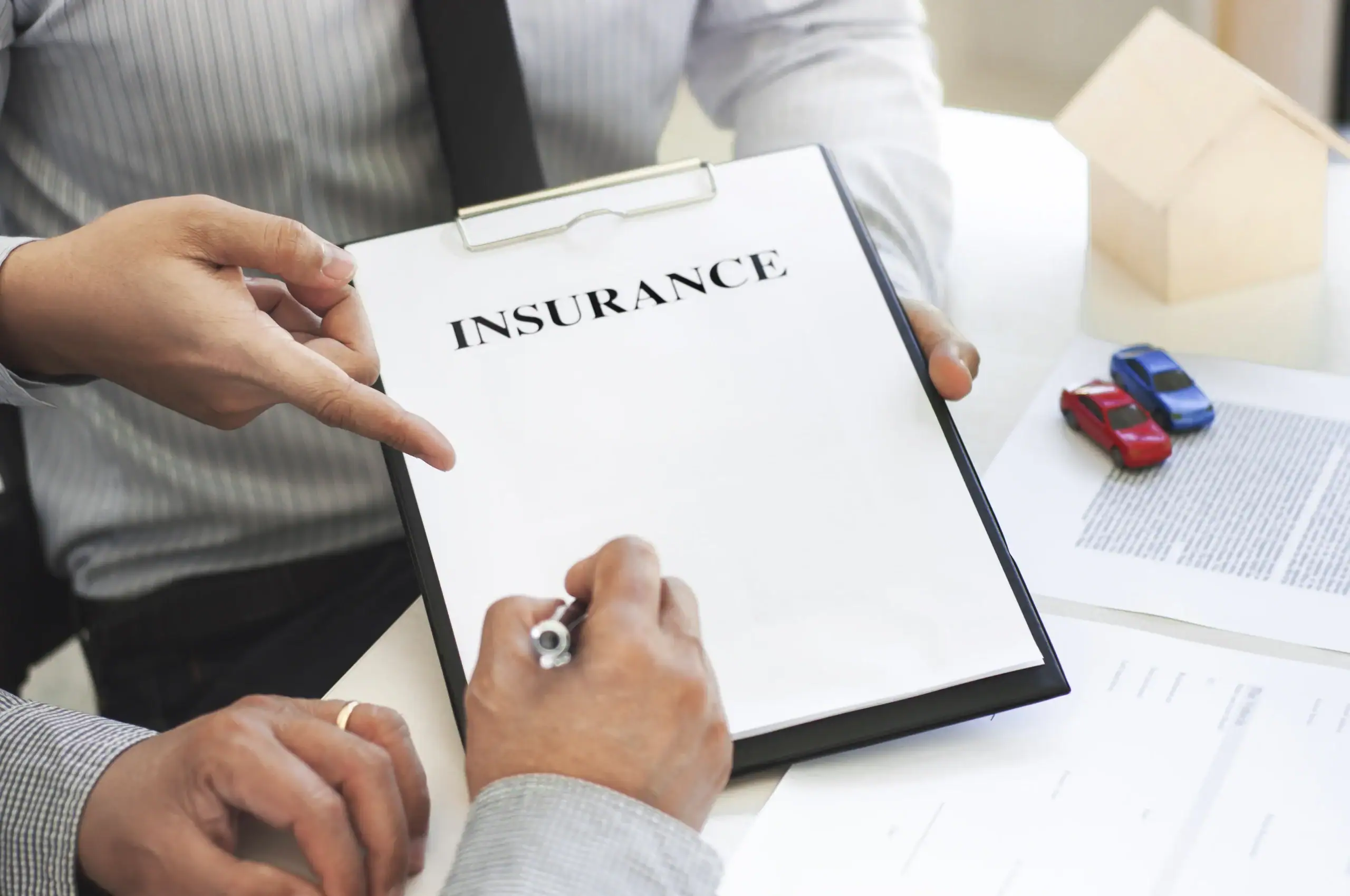 Two people review an insurance form together, with one ready to sign the paperwork on a clipboard.